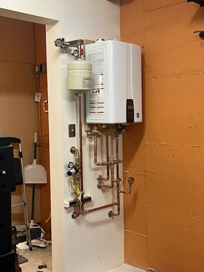Plumbing technician inspecting water heater connections in Edgartown